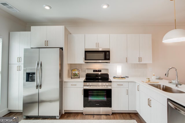 kitchen with sink, white cabinets, decorative light fixtures, light hardwood / wood-style floors, and appliances with stainless steel finishes