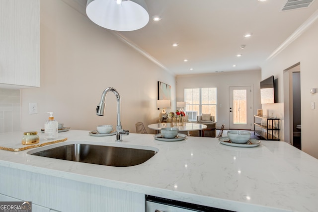 kitchen featuring sink, crown molding, and light stone countertops