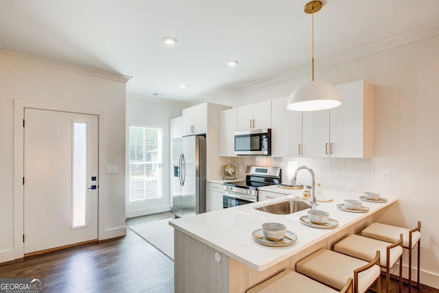 kitchen with stainless steel appliances, sink, white cabinetry, kitchen peninsula, and pendant lighting