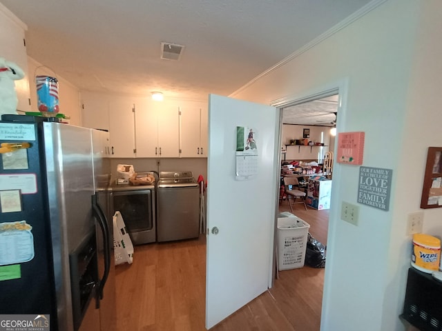 kitchen featuring washing machine and dryer, white cabinetry, light hardwood / wood-style floors, and stainless steel refrigerator with ice dispenser