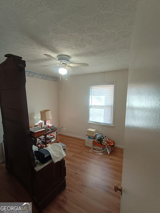 misc room featuring wood-type flooring, a textured ceiling, and ceiling fan