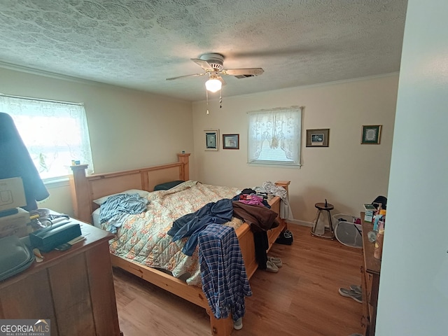 bedroom with ceiling fan, a textured ceiling, and light wood-type flooring