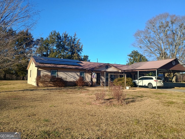 single story home with solar panels, a front lawn, and a carport