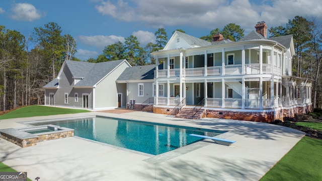 rear view of house with a pool with hot tub, a patio area, and a balcony