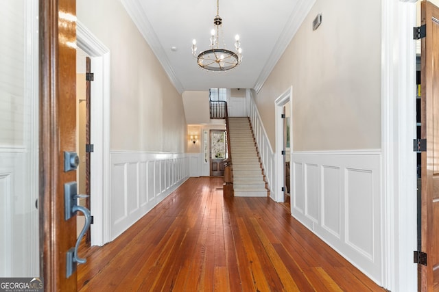 hallway featuring a notable chandelier, dark hardwood / wood-style flooring, and ornamental molding