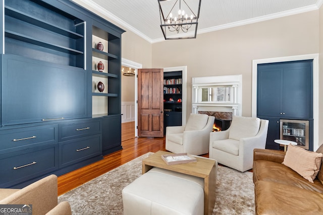 living room with built in shelves, crown molding, a chandelier, and dark hardwood / wood-style floors