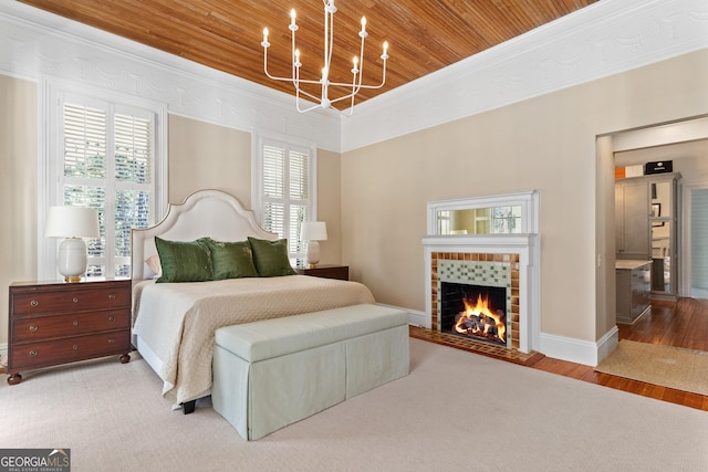 bedroom featuring crown molding, light hardwood / wood-style flooring, wooden ceiling, a chandelier, and a tiled fireplace