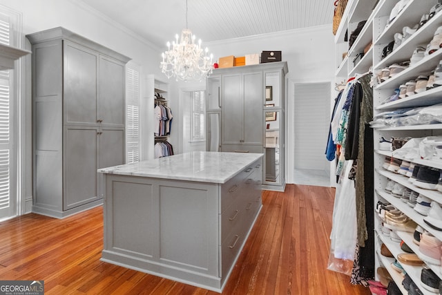 walk in closet with light hardwood / wood-style flooring and a notable chandelier