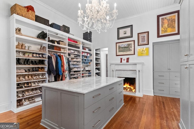 walk in closet with a fireplace, hardwood / wood-style flooring, and a chandelier