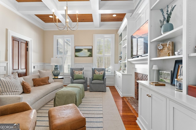 sitting room with a notable chandelier, ornamental molding, light hardwood / wood-style flooring, and coffered ceiling