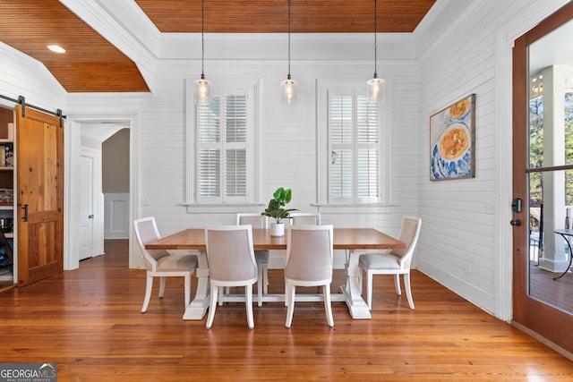 dining space featuring wood ceiling, vaulted ceiling, wood-type flooring, a barn door, and wood walls