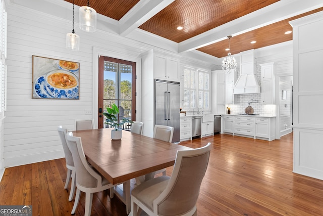 dining space with beam ceiling, light hardwood / wood-style floors, crown molding, and wooden ceiling