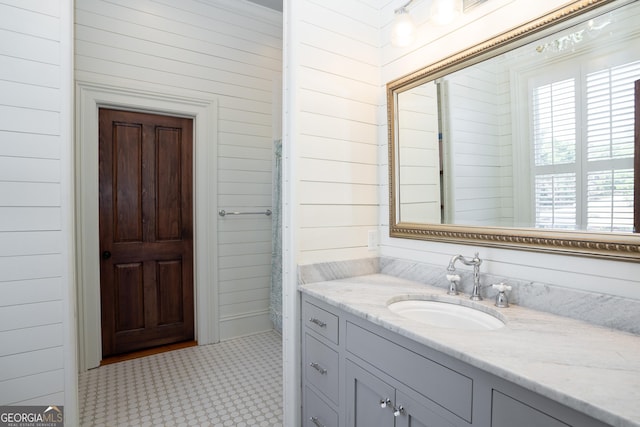 bathroom with tile patterned floors, vanity, and wood walls