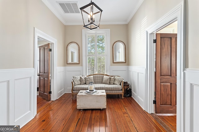 living area featuring a notable chandelier, wood-type flooring, and ornamental molding