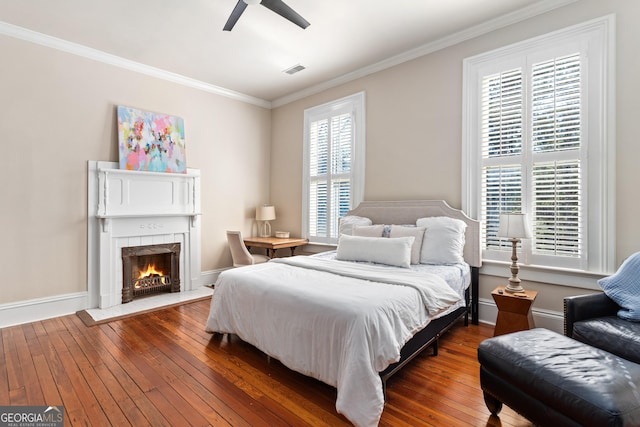 bedroom with multiple windows, dark hardwood / wood-style flooring, ceiling fan, and crown molding