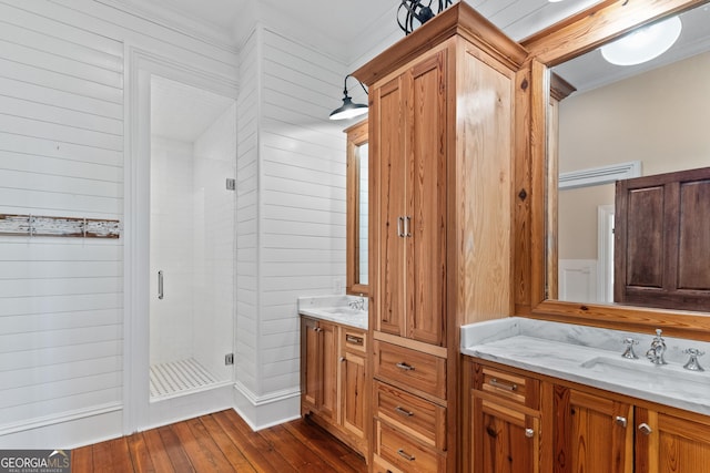 bathroom with vanity, wood-type flooring, a shower with door, and crown molding