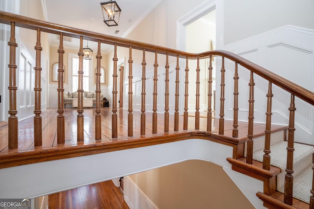 stairway featuring plenty of natural light, wood-type flooring, and ornamental molding