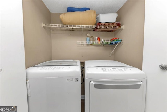 clothes washing area with independent washer and dryer and a textured ceiling