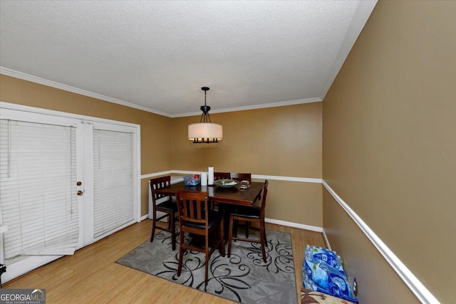 dining space featuring hardwood / wood-style floors, a textured ceiling, and ornamental molding