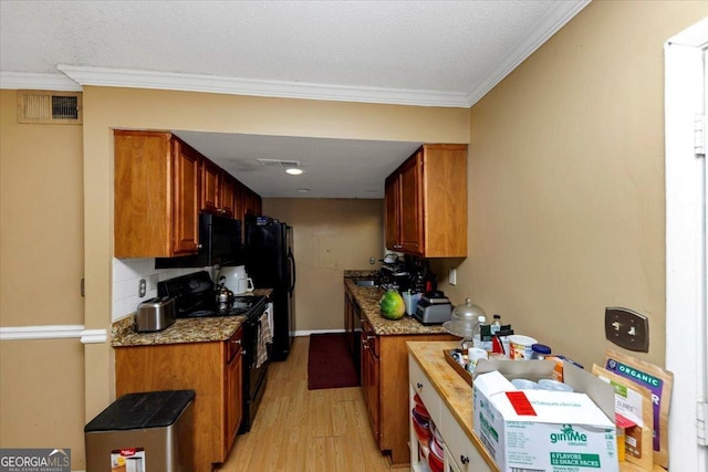 kitchen with light stone counters, light wood-type flooring, a textured ceiling, black appliances, and ornamental molding