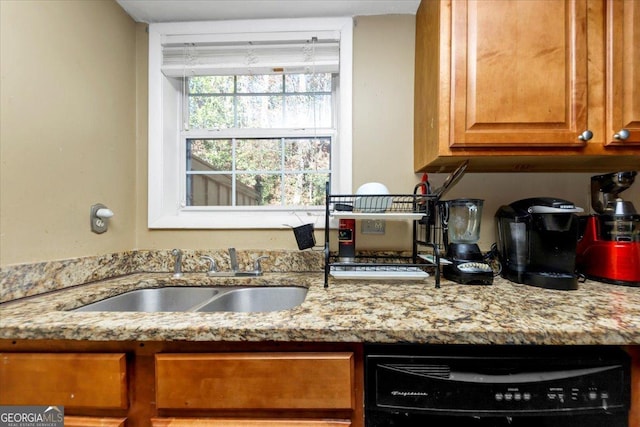 kitchen with dishwashing machine, light stone counters, and sink