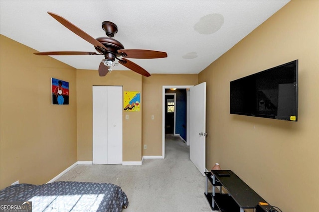 carpeted bedroom with ceiling fan, a textured ceiling, and a closet