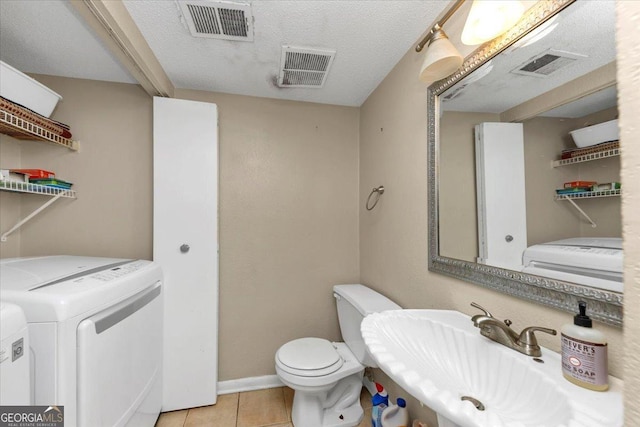 bathroom featuring sink, independent washer and dryer, tile patterned floors, a textured ceiling, and toilet