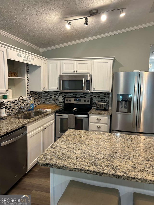 kitchen with tasteful backsplash, white cabinets, stainless steel appliances, and stone countertops