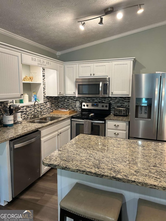 kitchen featuring backsplash, white cabinetry, light stone countertops, and appliances with stainless steel finishes