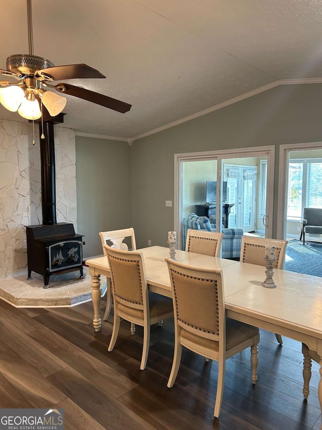 dining area with a wood stove, ceiling fan, hardwood / wood-style floors, lofted ceiling, and ornamental molding