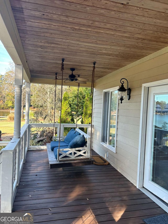 wooden terrace with ceiling fan, a water view, and covered porch