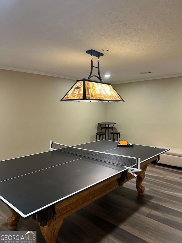 rec room with dark hardwood / wood-style flooring, a textured ceiling, and ornamental molding