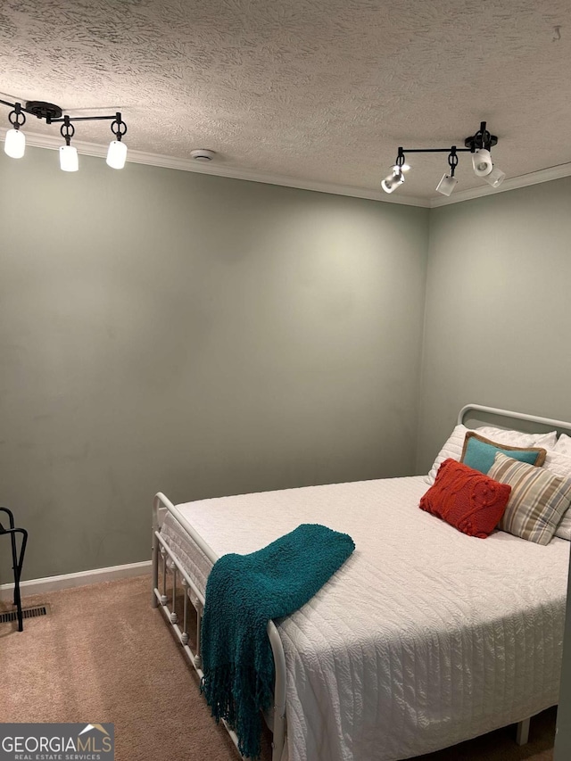 bedroom with carpet flooring, a textured ceiling, rail lighting, and crown molding