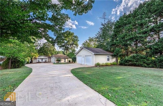 view of front of home featuring a garage, an outbuilding, and a front lawn