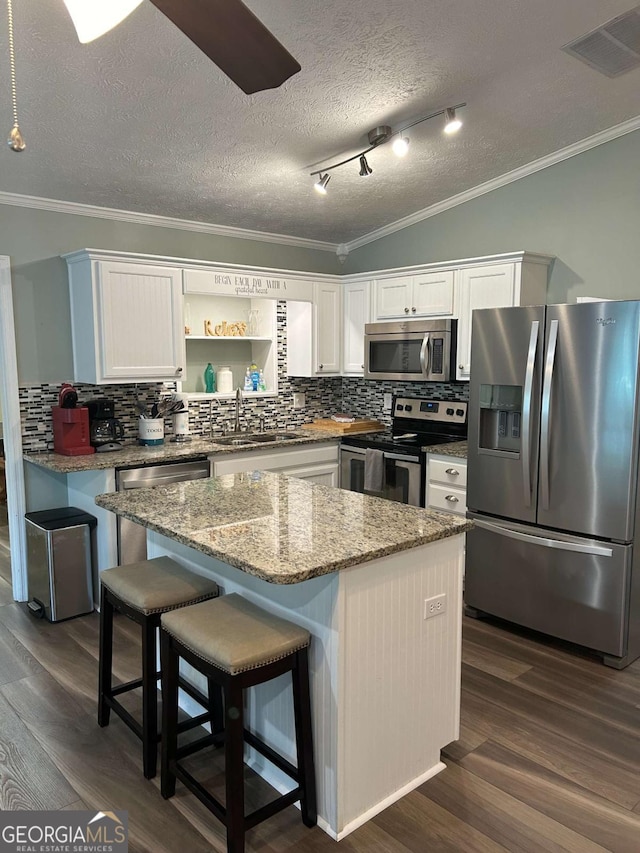 kitchen featuring a kitchen island, sink, appliances with stainless steel finishes, and tasteful backsplash