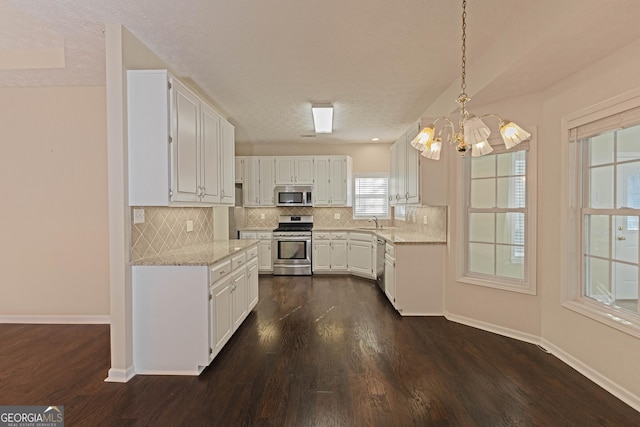 kitchen with white cabinetry, an inviting chandelier, decorative light fixtures, decorative backsplash, and appliances with stainless steel finishes