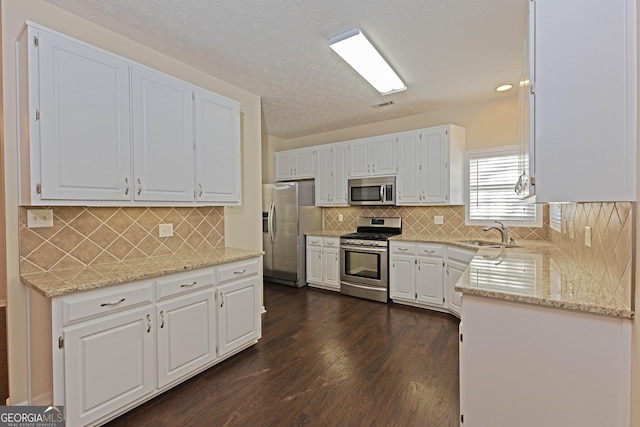 kitchen with light stone countertops, white cabinetry, sink, stainless steel appliances, and dark hardwood / wood-style floors