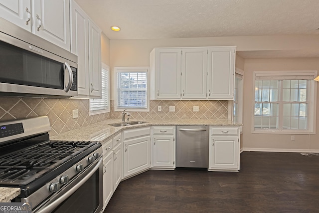 kitchen featuring appliances with stainless steel finishes, light stone counters, white cabinetry, and sink