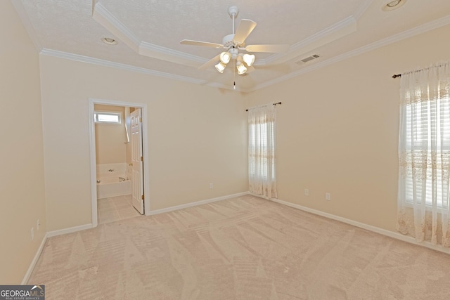 empty room featuring ceiling fan, light colored carpet, ornamental molding, and a tray ceiling