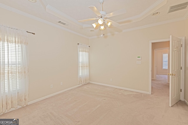 carpeted empty room featuring ceiling fan, a raised ceiling, and ornamental molding