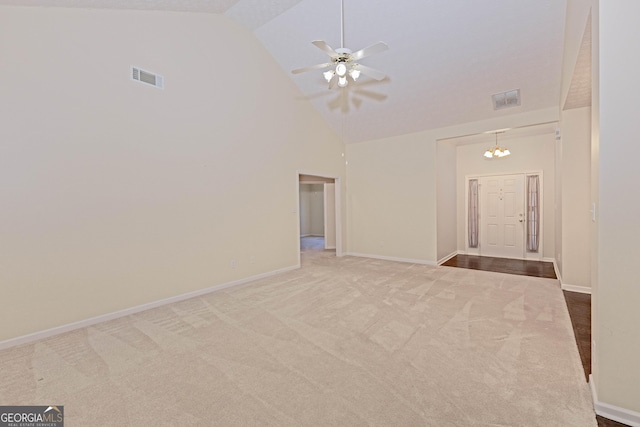 carpeted empty room featuring ceiling fan with notable chandelier and high vaulted ceiling