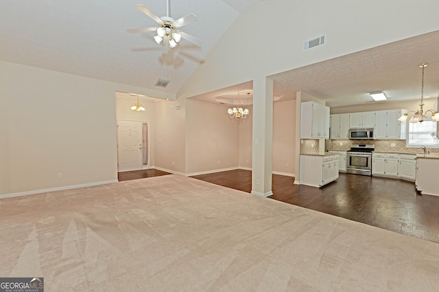 unfurnished living room with sink, high vaulted ceiling, ceiling fan with notable chandelier, and dark colored carpet