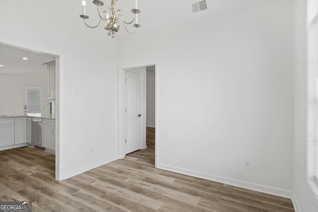 unfurnished room with an inviting chandelier and light hardwood / wood-style floors