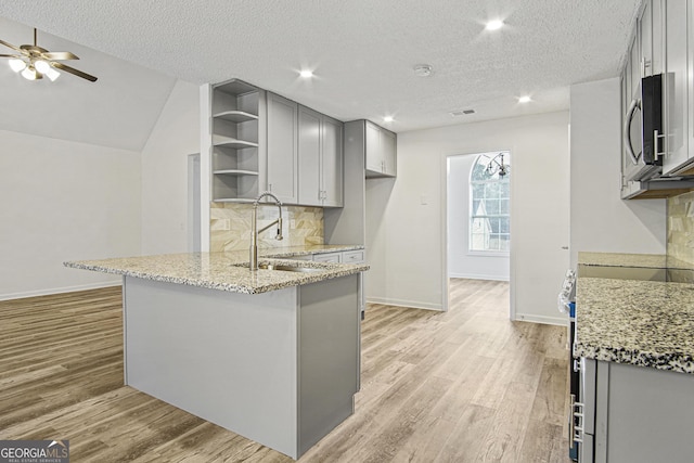 kitchen with appliances with stainless steel finishes, sink, tasteful backsplash, light stone countertops, and a textured ceiling