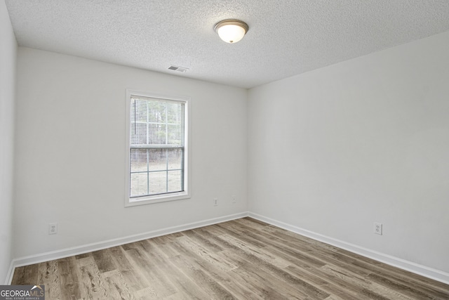 empty room featuring a textured ceiling and light hardwood / wood-style flooring