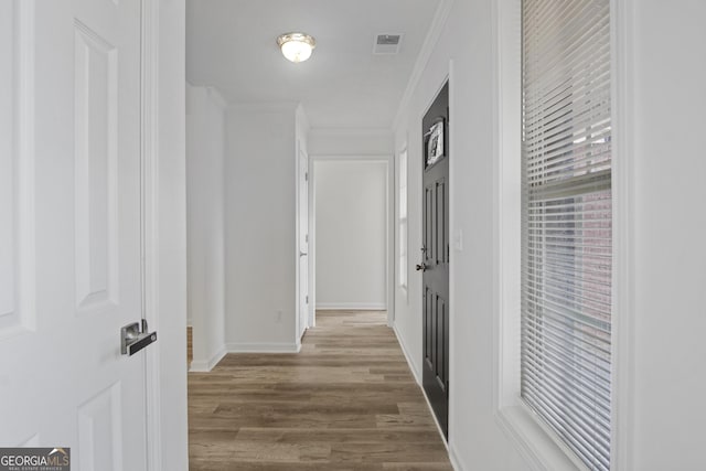 corridor with hardwood / wood-style floors and ornamental molding