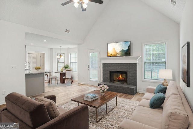 living room with light wood-type flooring, high vaulted ceiling, and a wealth of natural light