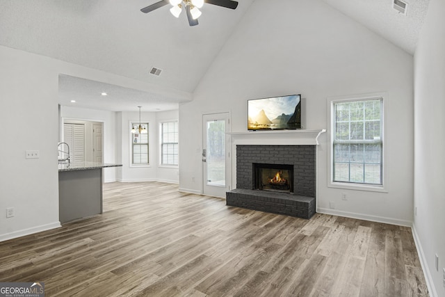 unfurnished living room featuring high vaulted ceiling, light wood-type flooring, and a healthy amount of sunlight