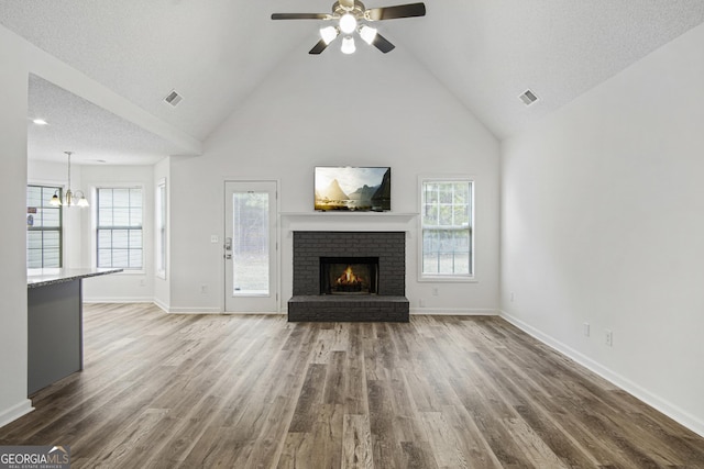 unfurnished living room featuring high vaulted ceiling, dark wood-type flooring, plenty of natural light, and a fireplace