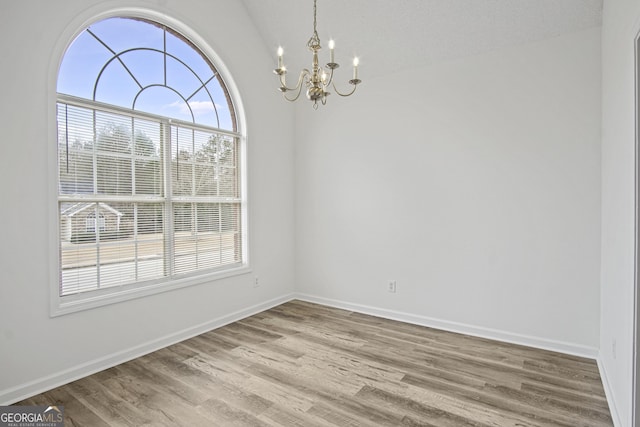 unfurnished dining area with lofted ceiling, hardwood / wood-style flooring, a textured ceiling, and a notable chandelier